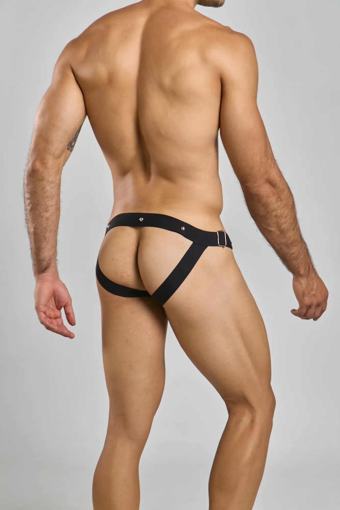 Black leather-like dngeon snap jockstrap briefs with a central belt and side straps in a harness style