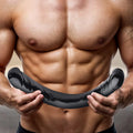 A muscular man holding a sleek, black Doc Johnson Enterprises double-ended dildo with curved design.