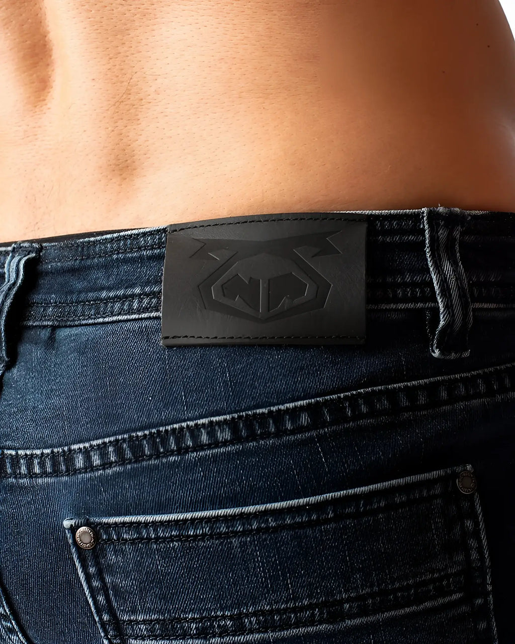 Black leather patch with embossed logo on the back of dark blue denim duke short jeans
