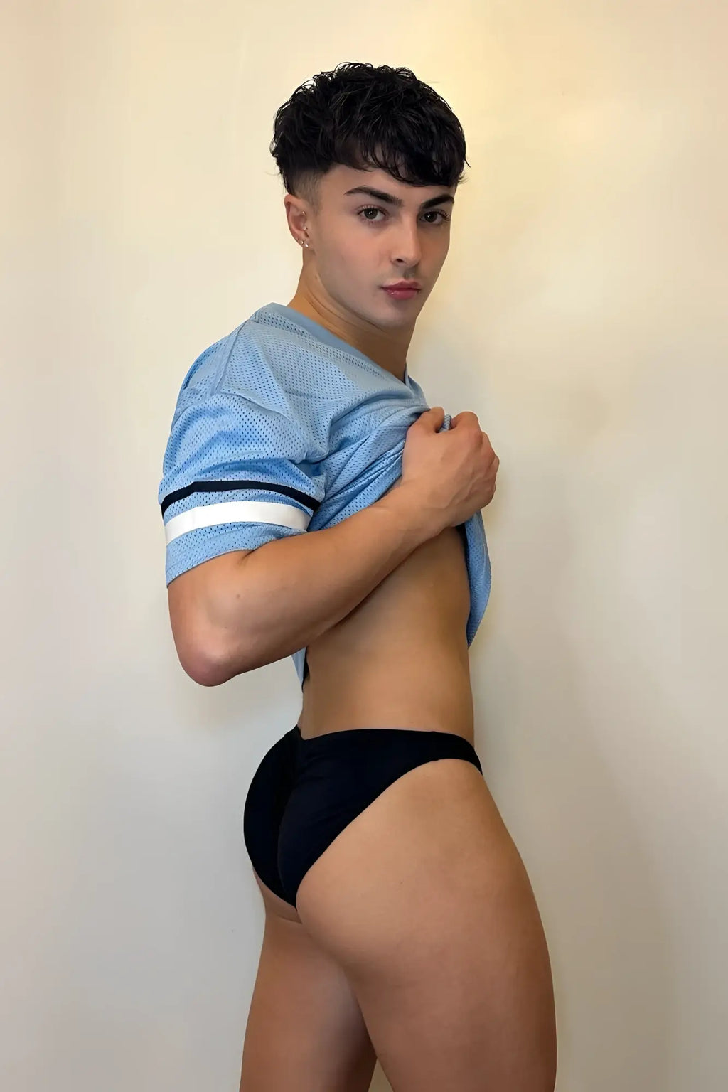 Light blue mesh football jersey with white and black stripes on sleeves shown from the back with jet black scrunch-butt brief
