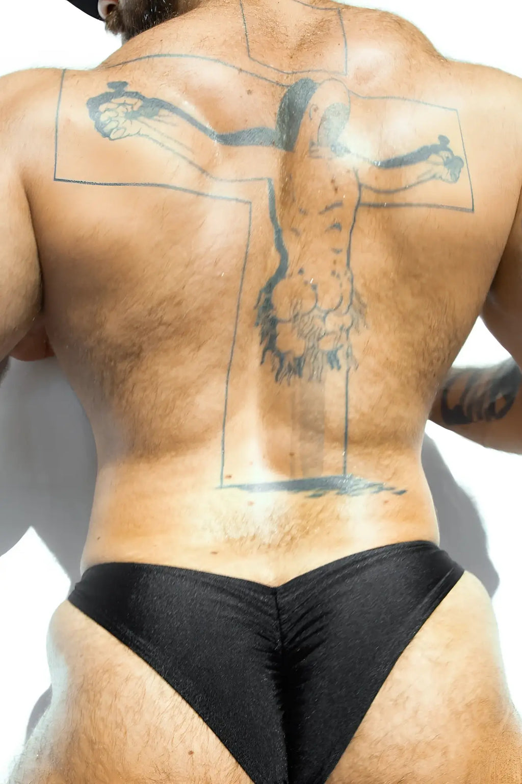 Black shiny form-fitting swim trunks with scrunch butt detail in jet black showing the back side of the brief