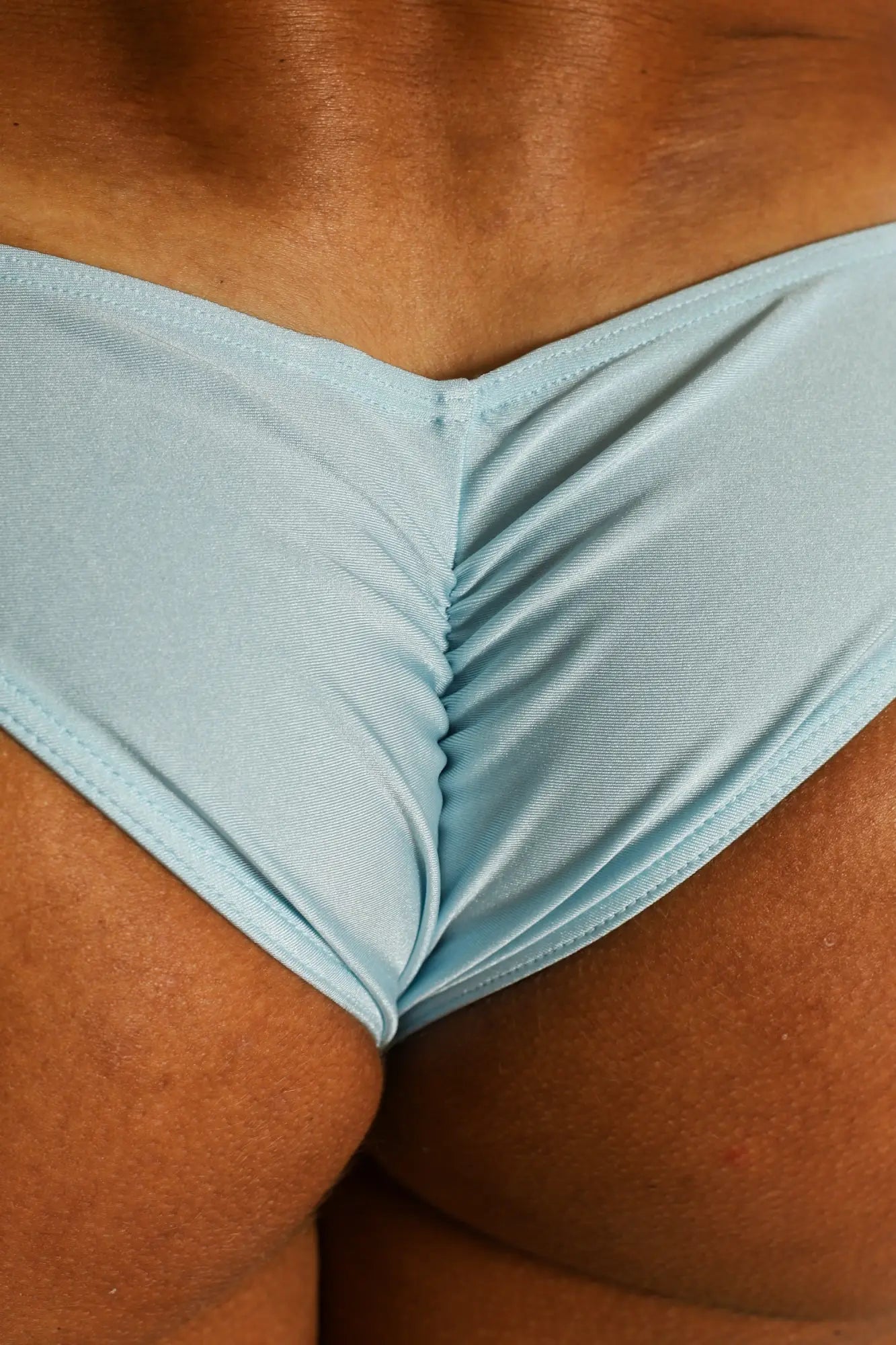 Light blue dynamic scrunch-butt bikini briefs with v-shaped front and subtle ribbed texture in a form-fitting style