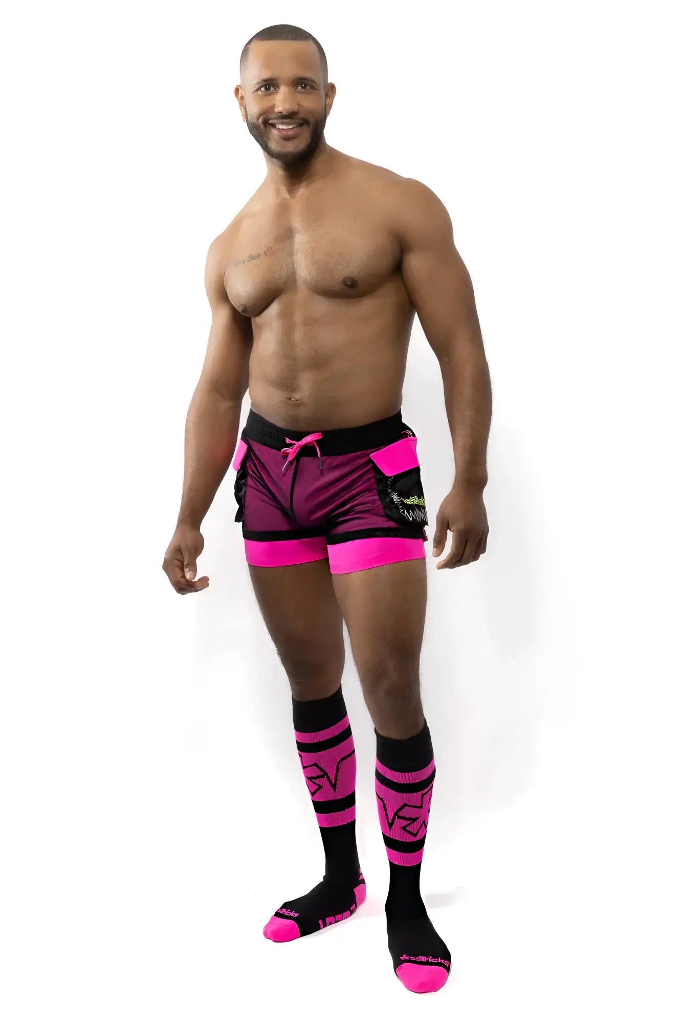 The man is wearing vibrant pink and black electric cargo shorts with a matching logo on the side for athletic use