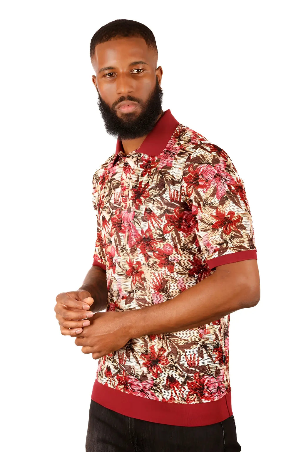A man wearing an entwine form polo shirt with a vibrant red pink and brown floral pattern on light beige fabric