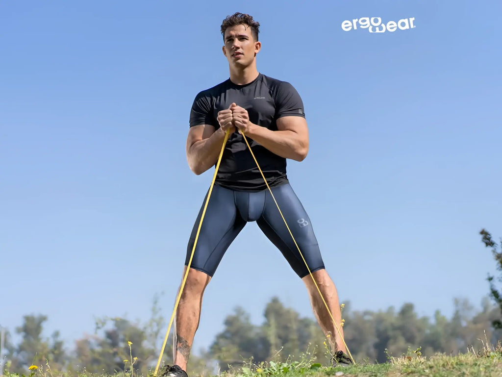 A man wearing ErgoWear ew1607 max se dark blue compression athletic shorts holding yellow resistance bands