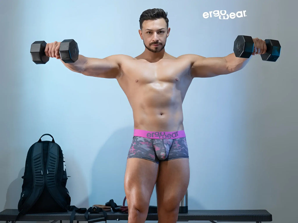 Black hexagonal dumbbells beside pink camo ergoWear ew1716 max se trunks for comfortable workout wear