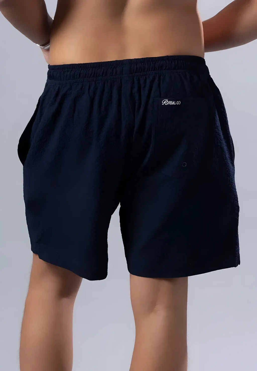 Dark navy blue essential swim short with elastic waistband and embroidered logo on back pocket shown from back side