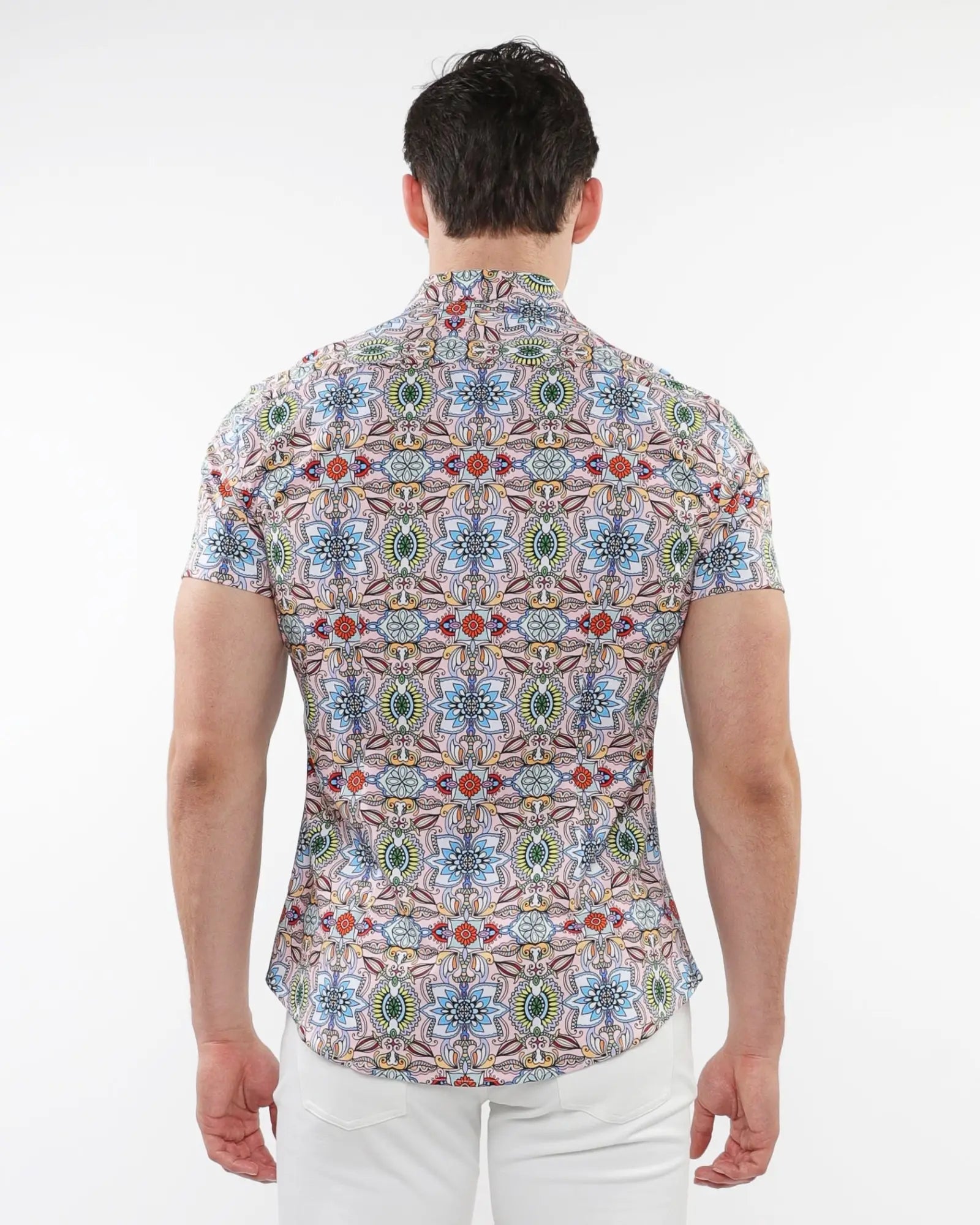 A man wearing a fauna print stretch knit short-sleeved shirt with colorful geometric and floral patterns on light background