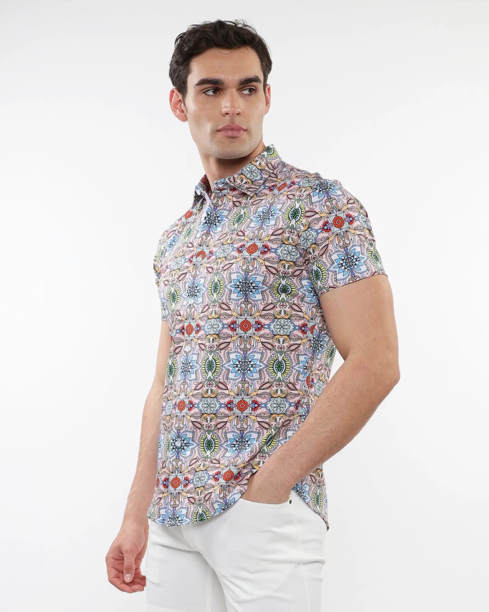 A man wearing a fauna print stretch knit short-sleeved shirt with colorful geometric and floral patterns on light background