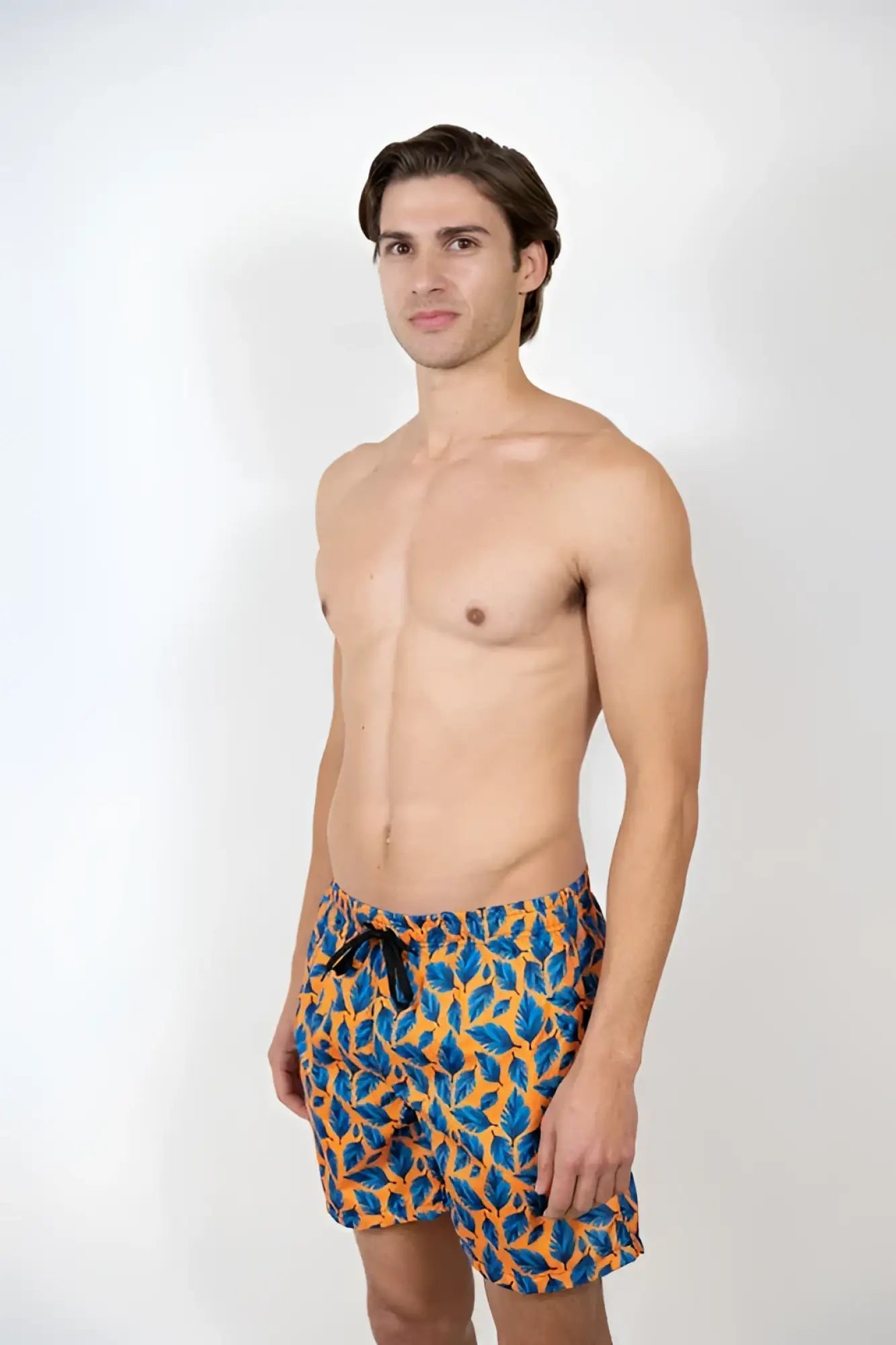 Men’s feather print swim shorts with vibrant blue and orange leaf pattern on stretch fabric and black drawstring waistband