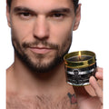 Gold-rimmed tin holding a black hot wax candle with lit wick labeled fever from the master series