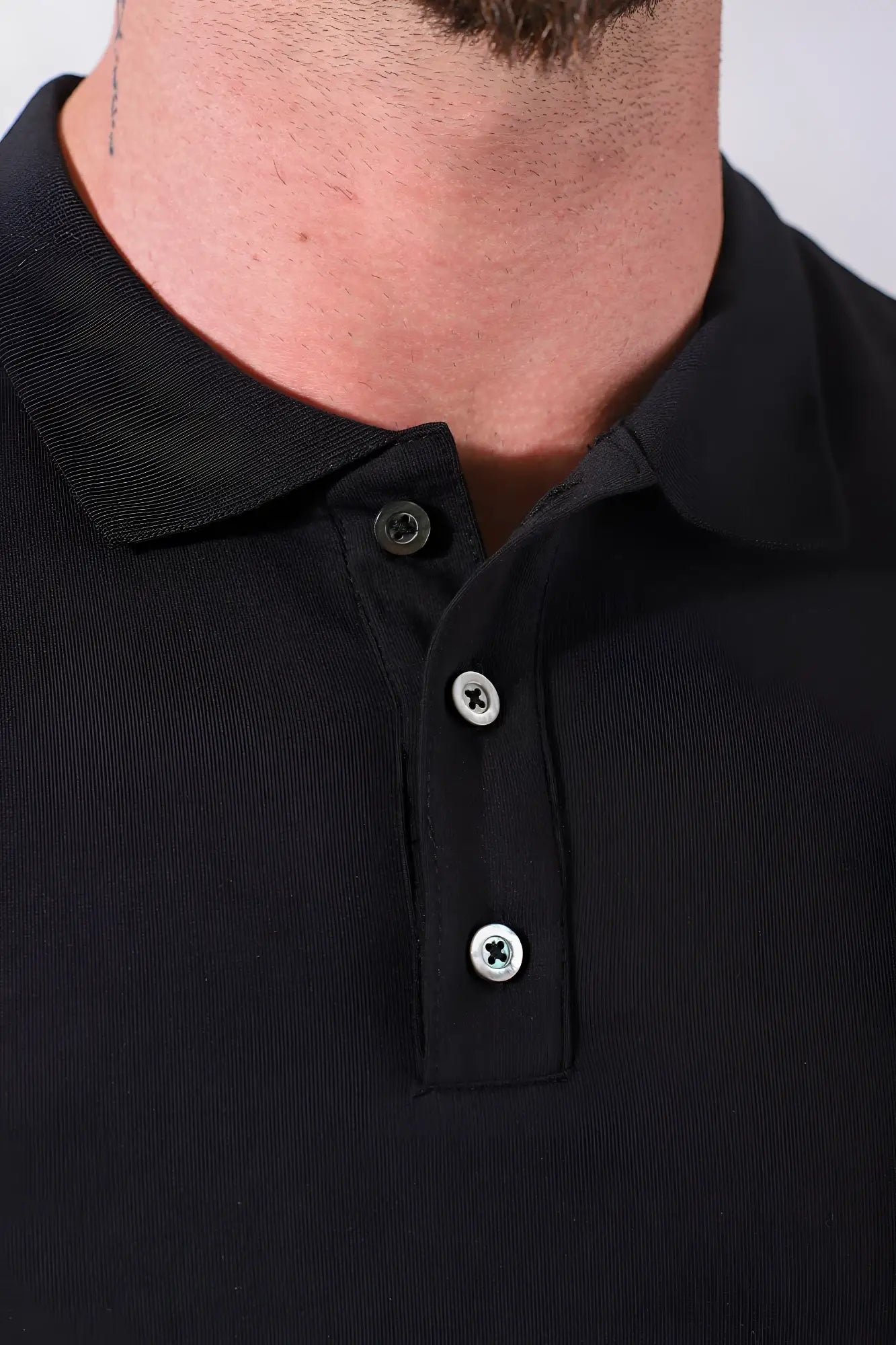 Fitted polo crop top in black with ribbed collar and three silver toned buttons made from soft fabric