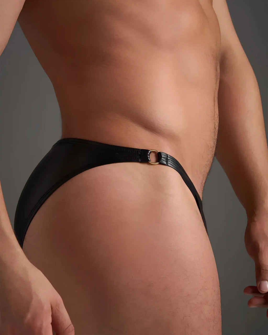 Black leather thong brief with a gold toned metal ring at the waistband flexible fit design