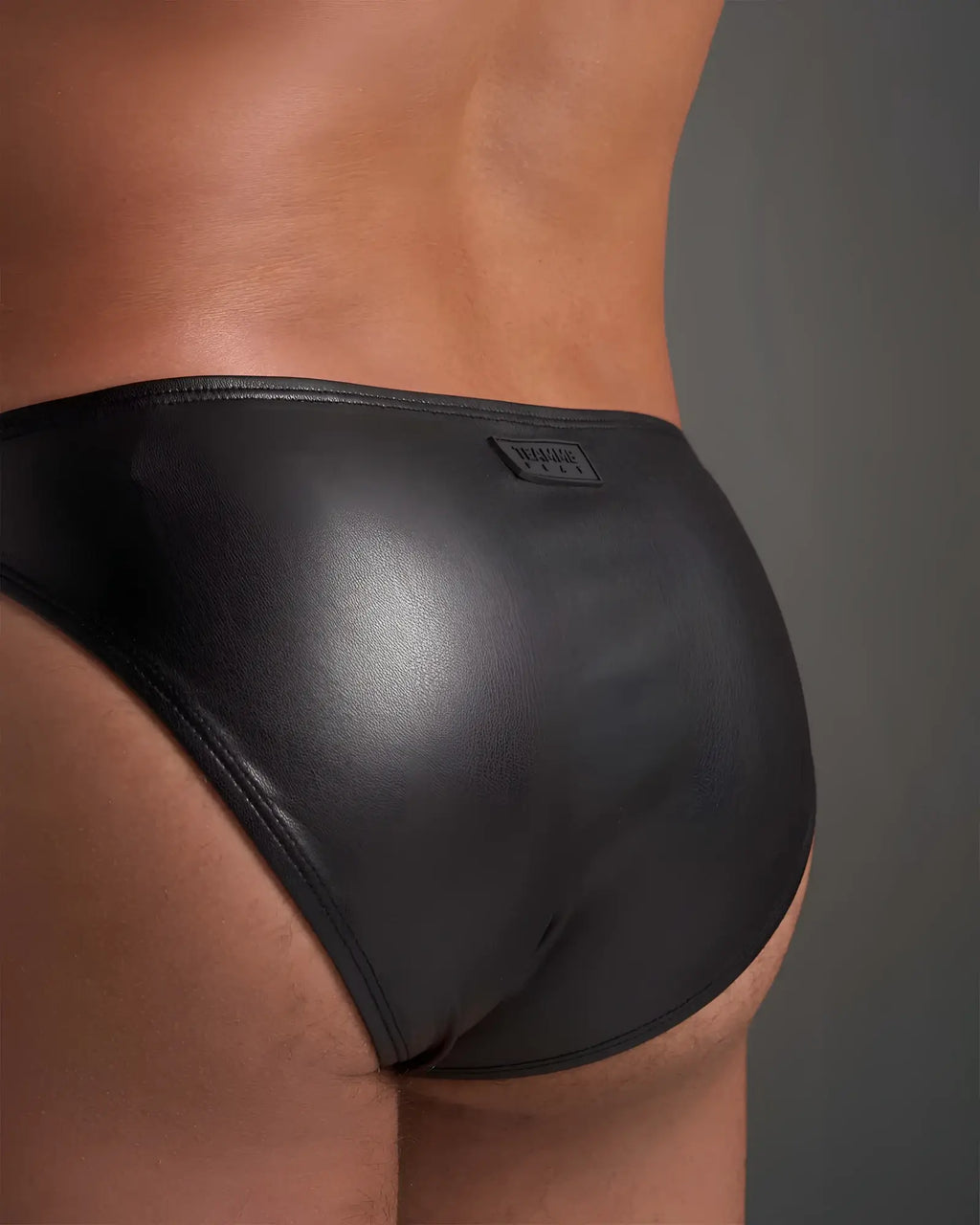 Black patent leather flex brief with a small rectangular brand tag on the waistband