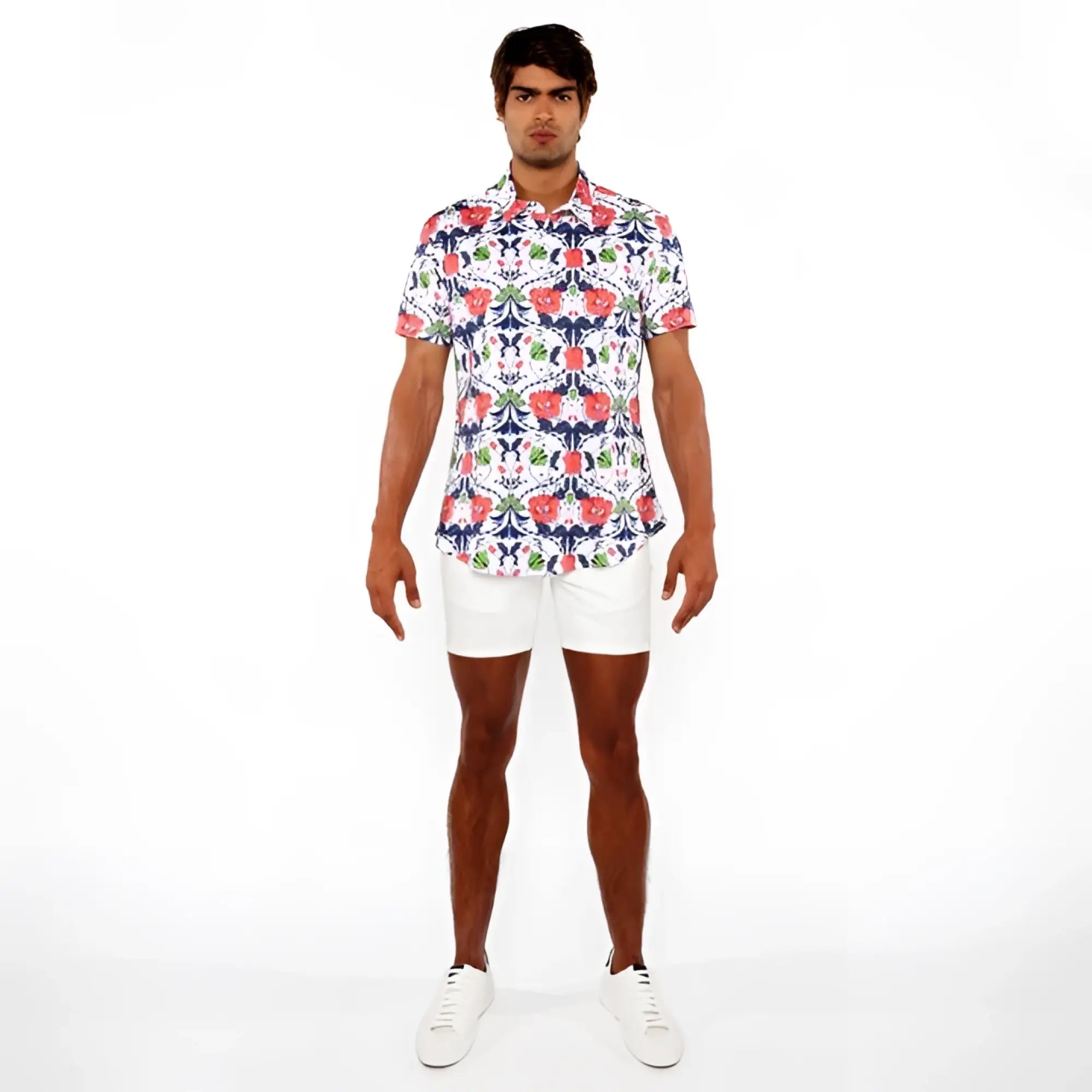 A man wearing a floral print stretch knit shirt with vibrant red blue and green flowers on a white background