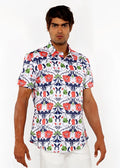A man wearing a white floral print stretch knit shirt with red poppies green leaves and navy blue accents