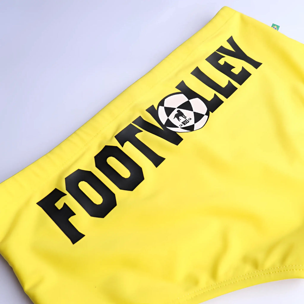 Bright yellow men’s footvolley sunga traditional cut swimwear with bold black lettering and integrated soccer ball logo