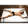 Frisky Beginner Fleece Bed Restraints Kit: A man in black briefs is restrained to a bed with black fleece cuffs.