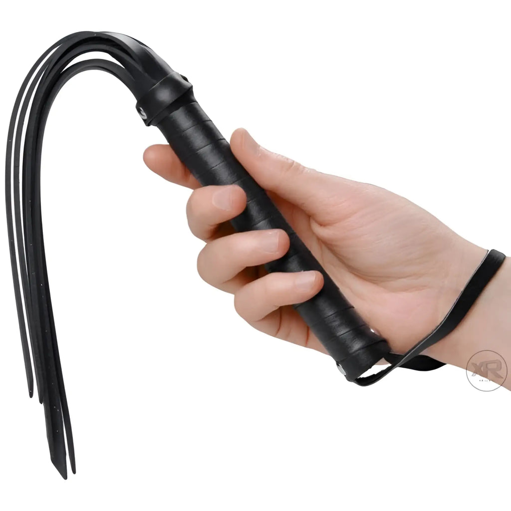 Hand holding a black Frisky Rubber Strand Mini-Flogger with thin, flexible rubber strips and a textured grip handle.