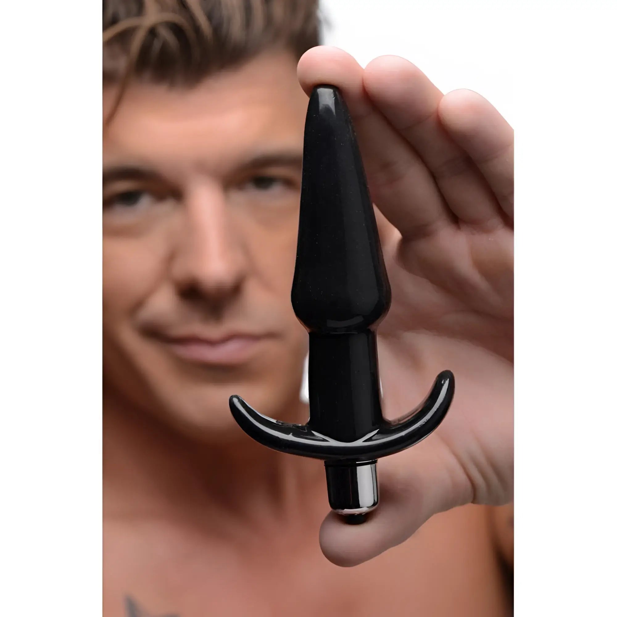 A man holds a smooth, glossy black Frisky Smooth Vibrating Anal Plug with a flared base against a white background.