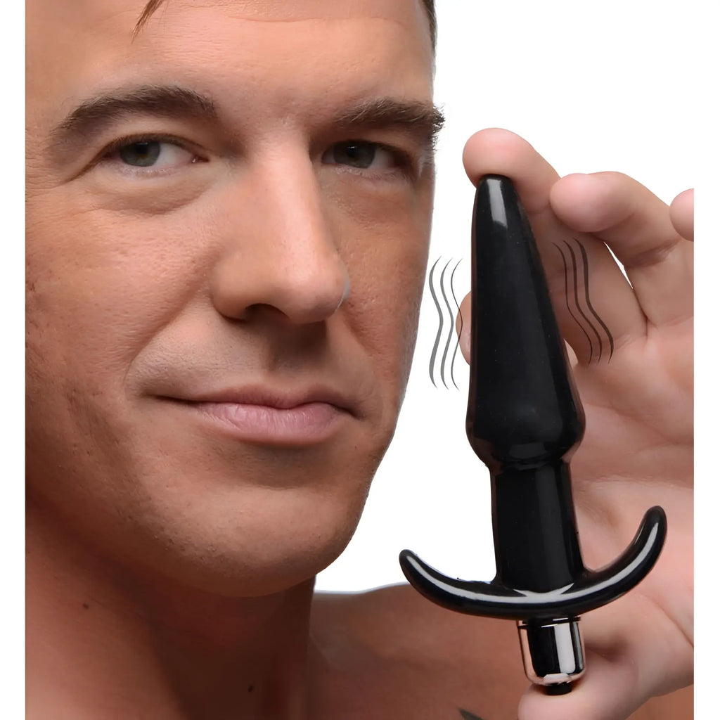 A man holding a smooth, black Frisky Smooth Vibrating Anal Plug with a silver base and motion-indicating lines.