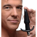 A man holding a smooth, black Frisky Smooth Vibrating Anal Plug with a silver base and motion-indicating lines.