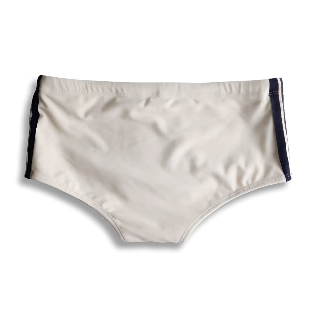 Cream-colored galão creme sunga designer swim shorts with navy blue side stripes for beachwear