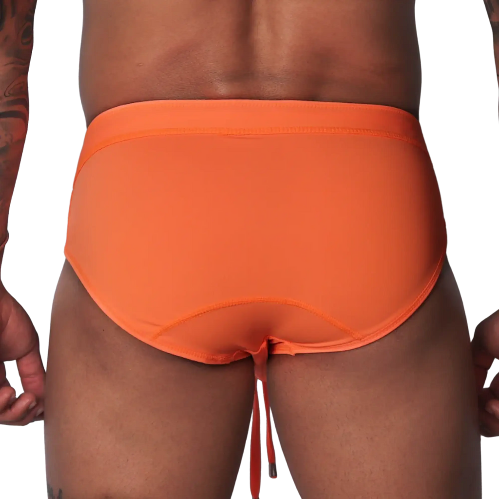 Bright orange swim brief with a wide waistband, contoured back seams, and dangling drawstring against black background.