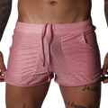 Pink mesh athletic shorts with a drawstring waistband, two side pockets, and a shorter, fitted cut.