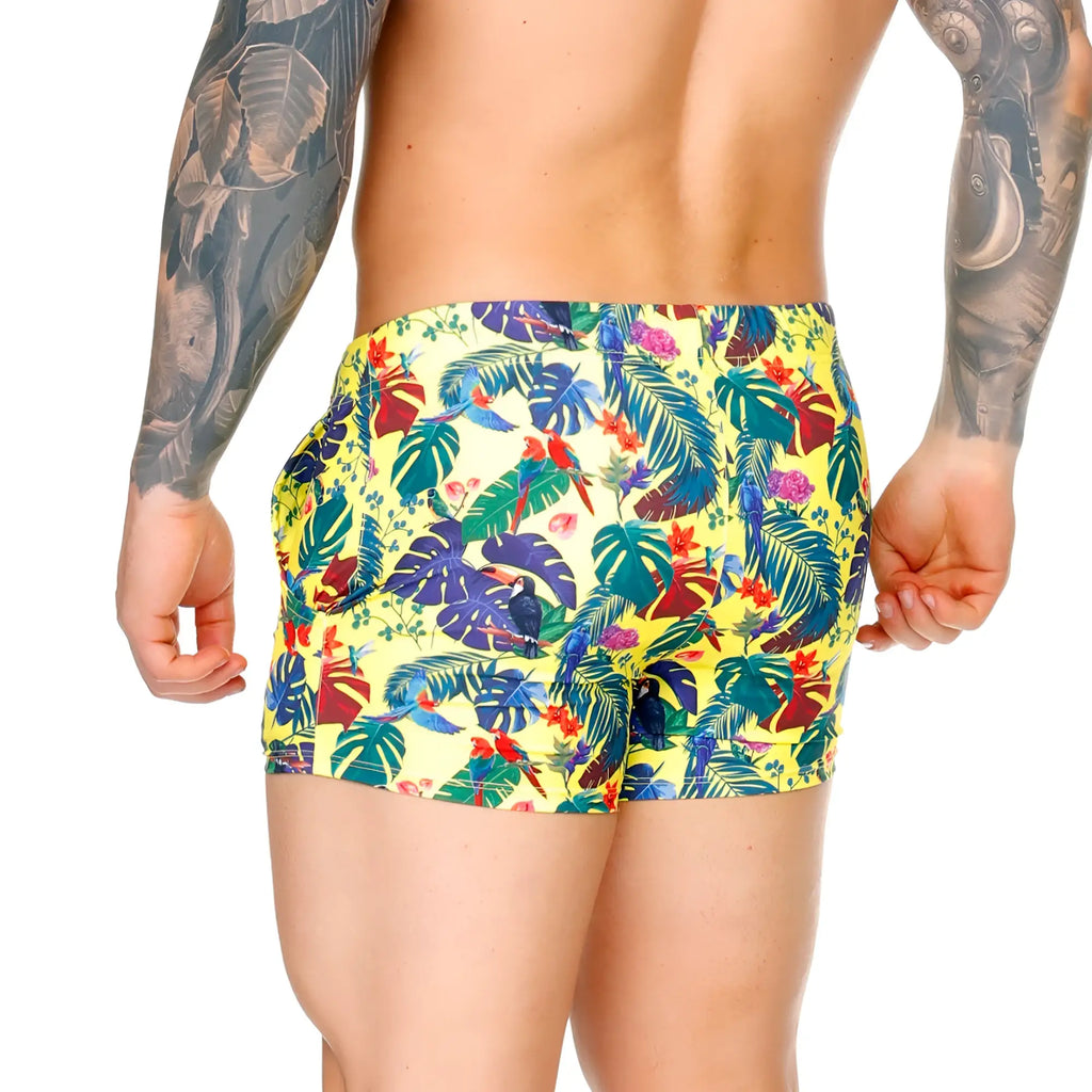 Vibrant yellow Gigo Macaws swim trunks with tropical print of green blue red and purple leaves and birds
