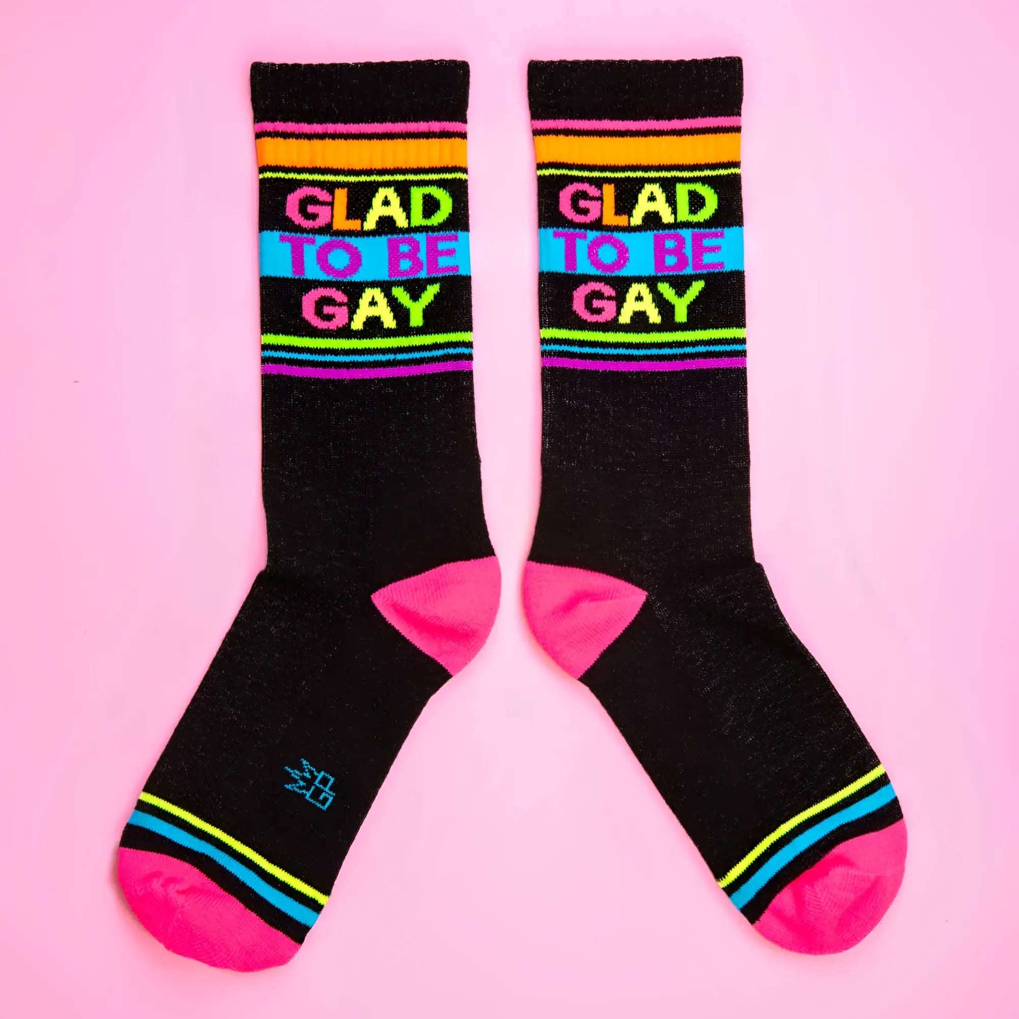 Black crew socks with vibrant rainbow stripes and glad to be gay in bold colorful letters across the top