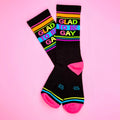 Black crew socks with vibrant rainbow stripes and bold colorful glad to be gay lettering on the top side