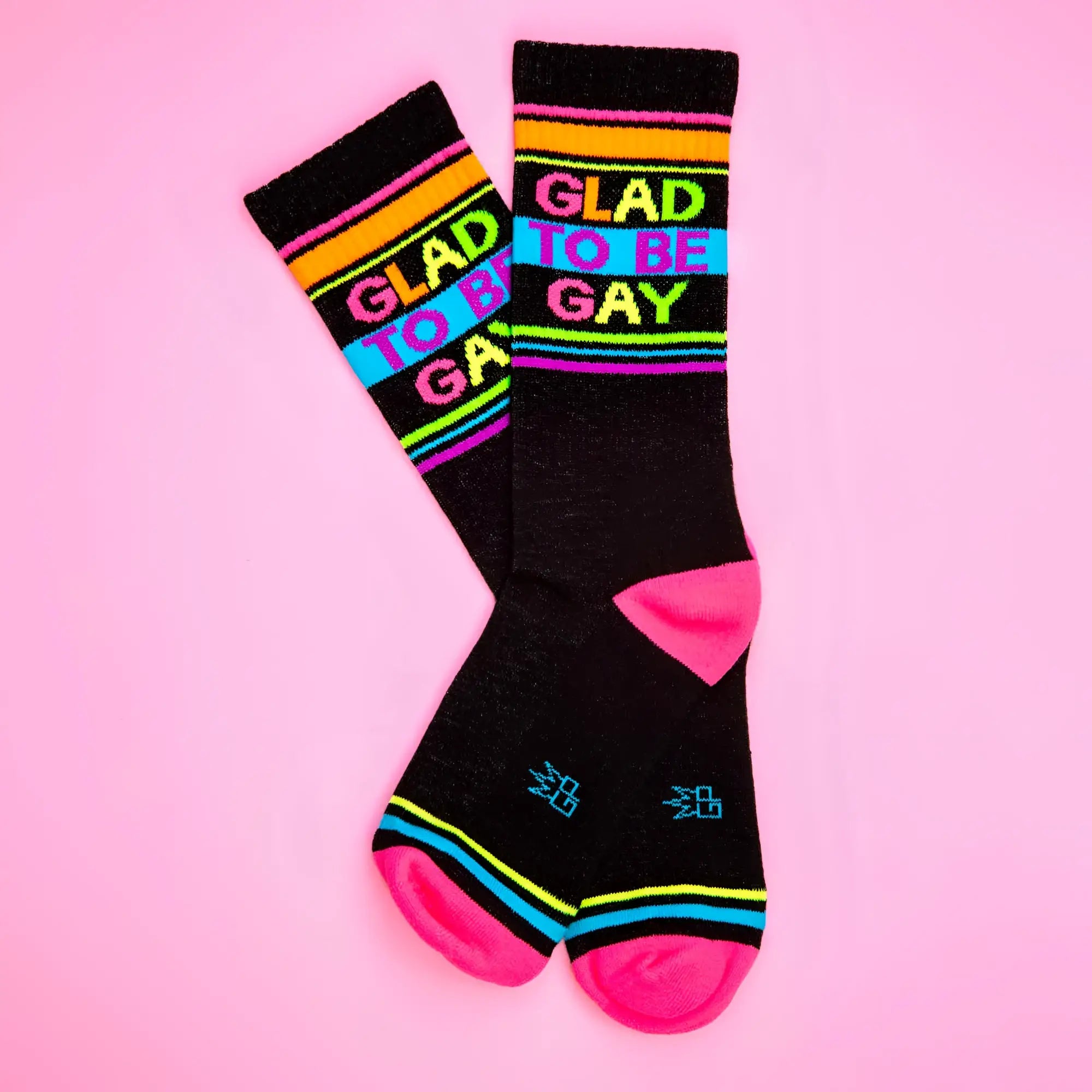 Black crew socks with vibrant rainbow stripes and bold colorful glad to be gay lettering on the top side