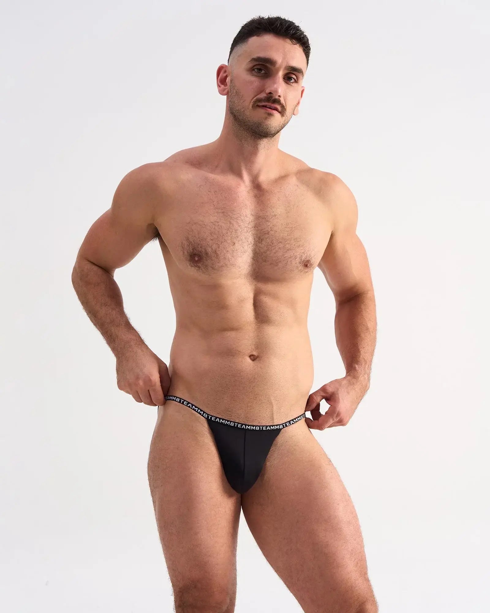 Black glide micro brief thong with white repeating logo waistband showing the back side of the underwear