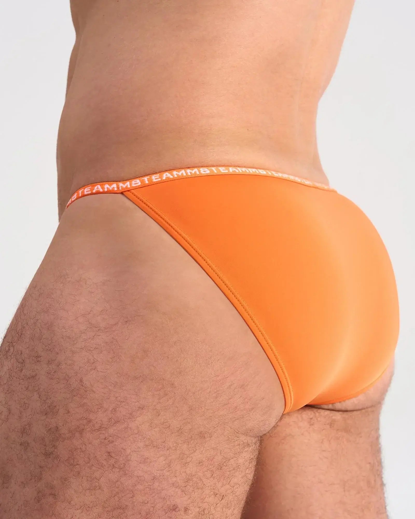 Bright orange glide micro brief with matching elastic waistband featuring brand’s repeating logo in front view