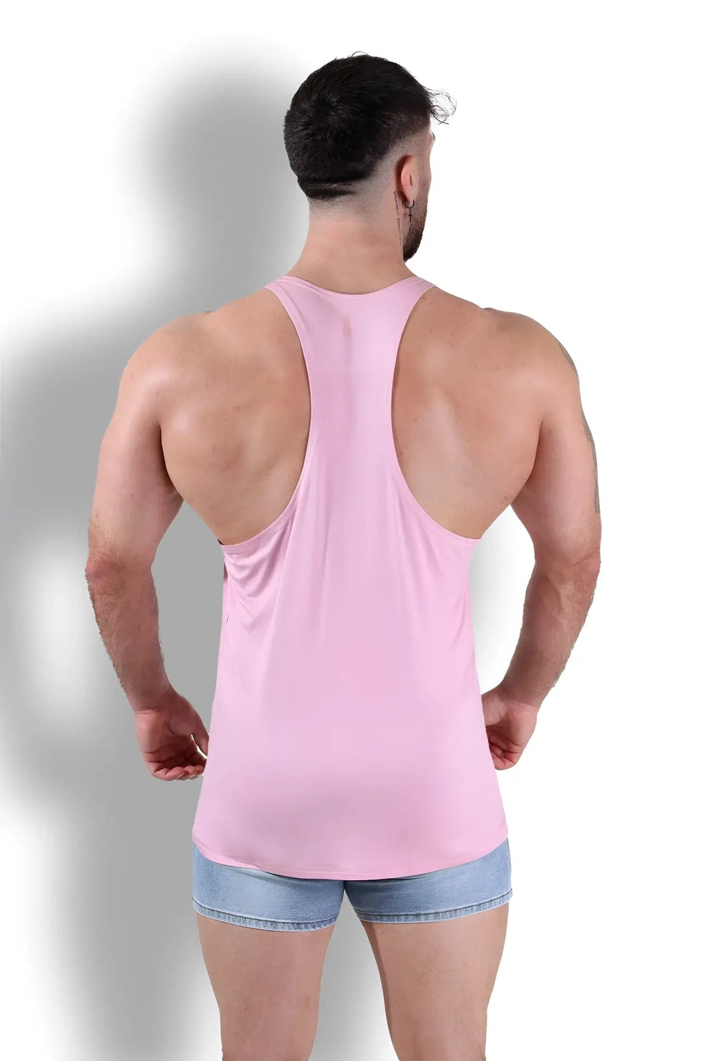 A man wearing a pink sleeveless gym bae classic workout stringer with a racerback design showing the back side