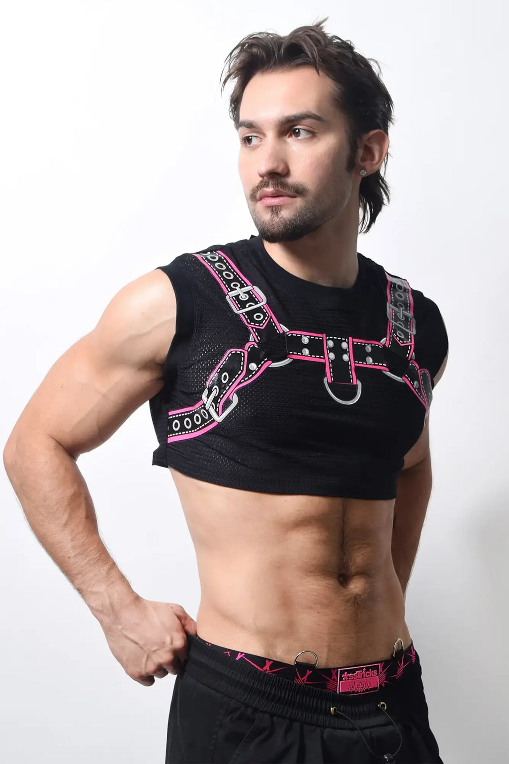 Black mesh harness crop top with pink and silver leather-like straps featuring metal buckles and d-rings