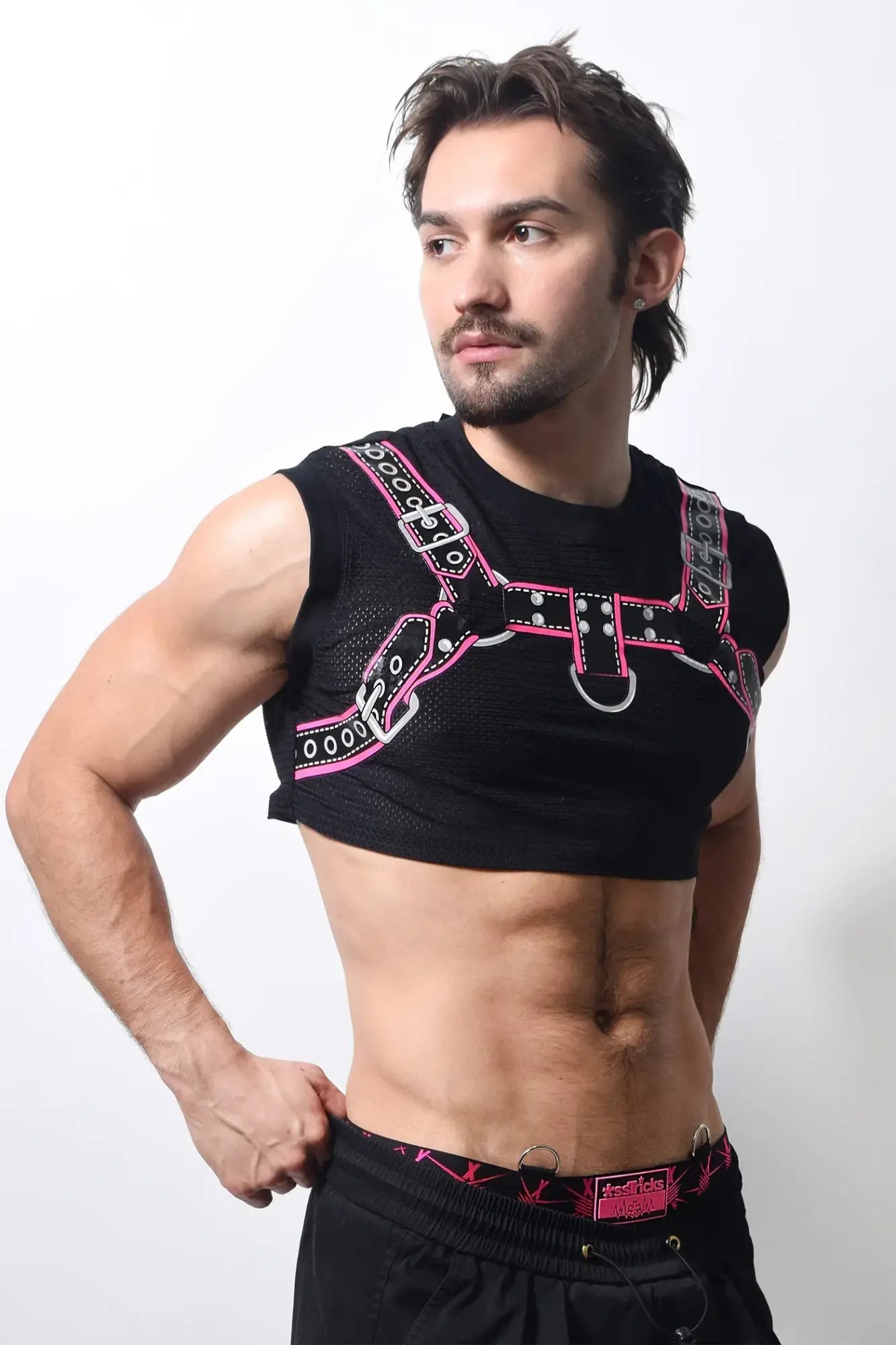 Black mesh harness crop top with pink and silver leather-like straps featuring metal buckles and d-rings
