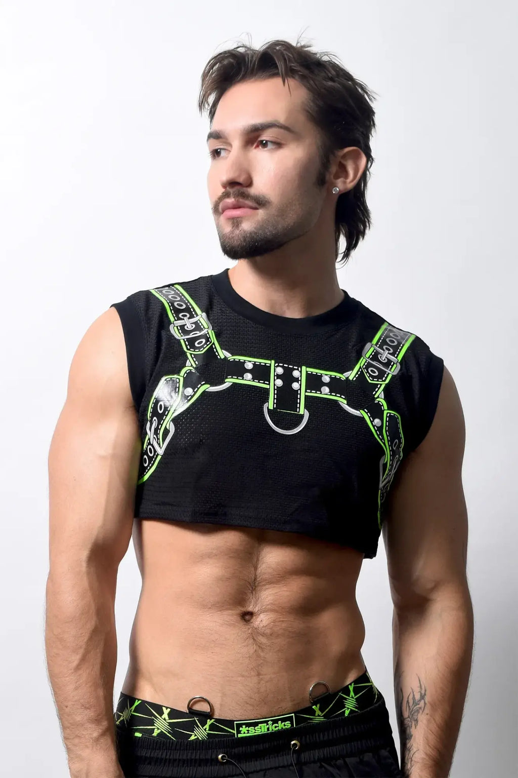 Black sleeveless harness crop top with neon green leather-like straps and silver hardware detailing