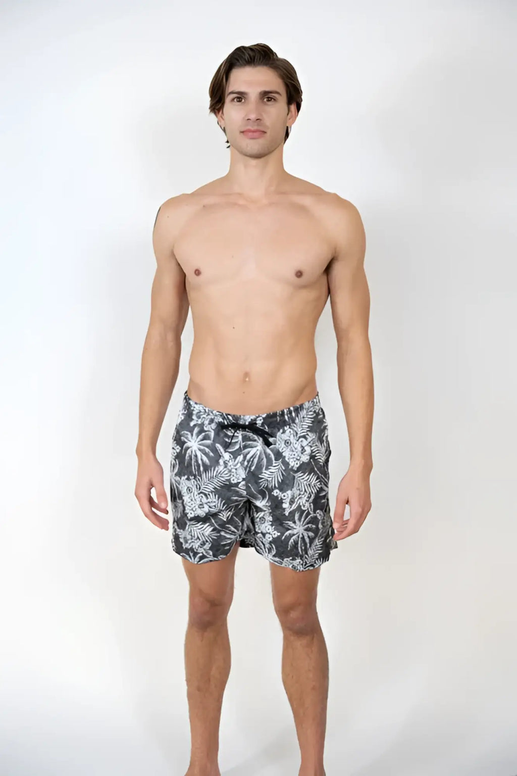 Men’s dark gray Hawaiian print swim shorts with white tropical leaf pattern and black drawstring waistband