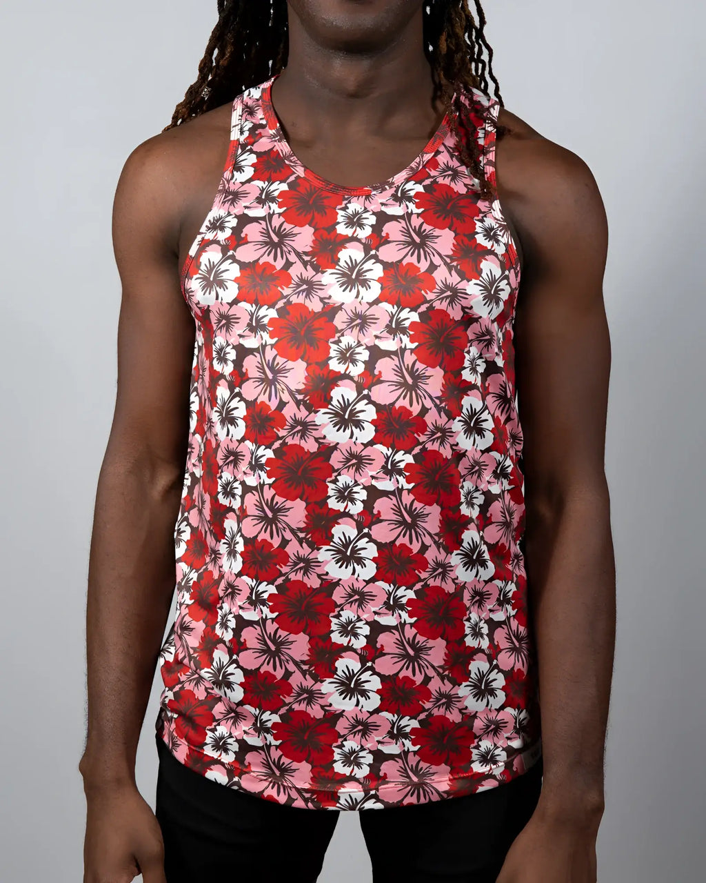 A Hawaiian hibiscus print tank top with vibrant red pink and white floral design and a round neckline