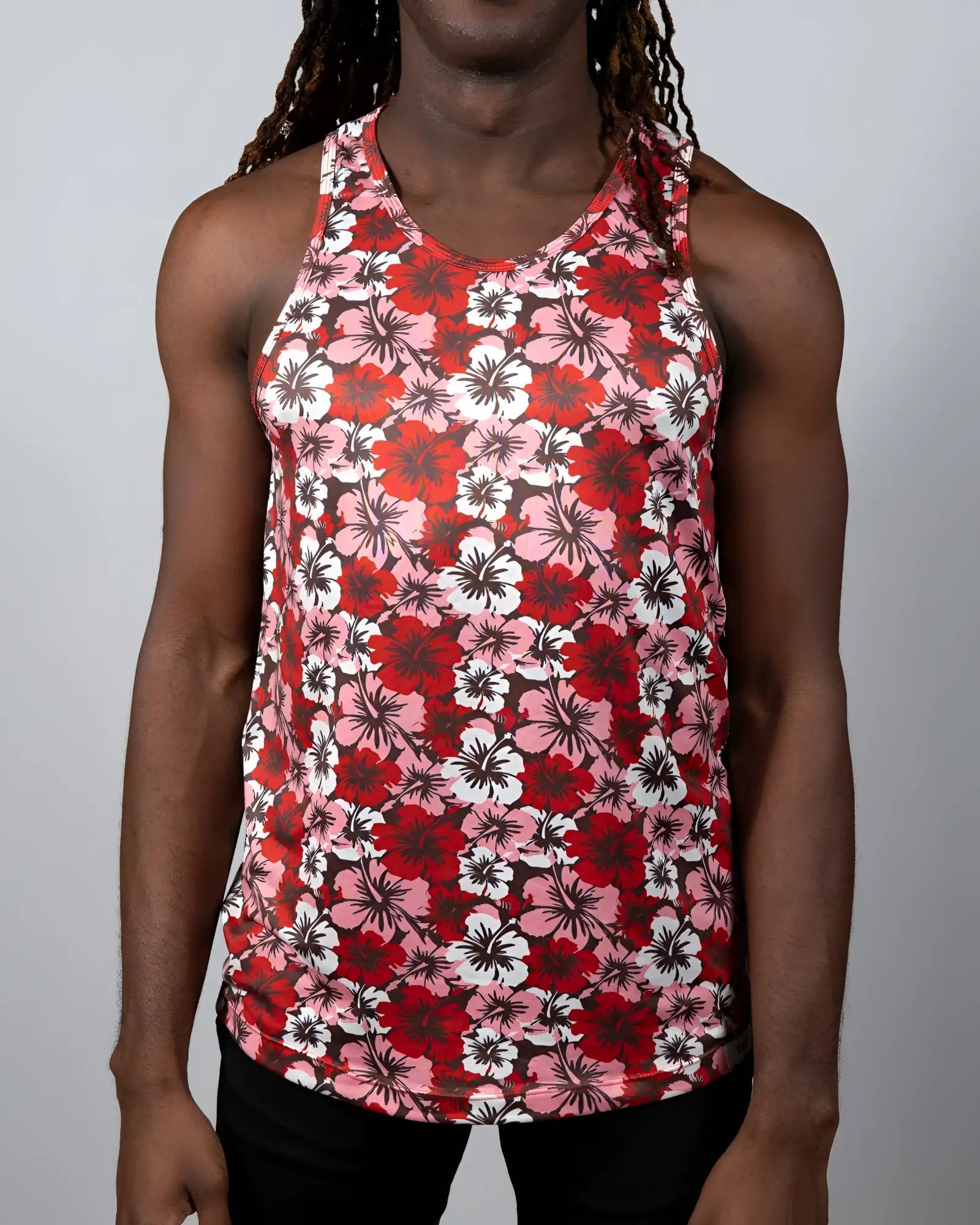 A Hawaiian hibiscus print tank top with vibrant red pink and white floral design and a round neckline
