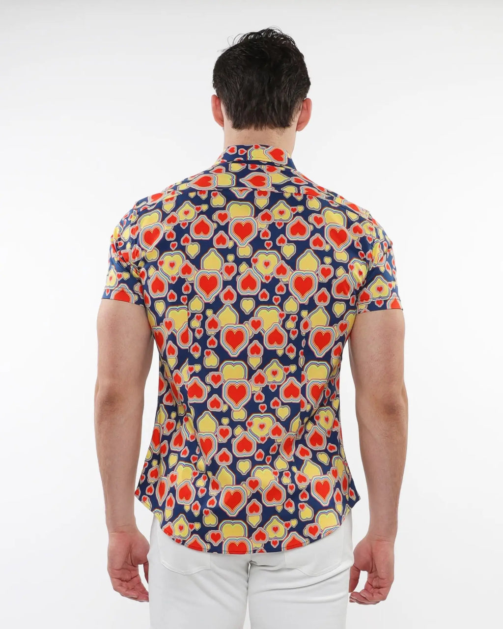 A man wearing a navy blue hearts print stretch knit short sleeve shirt with red and yellow heart patterns