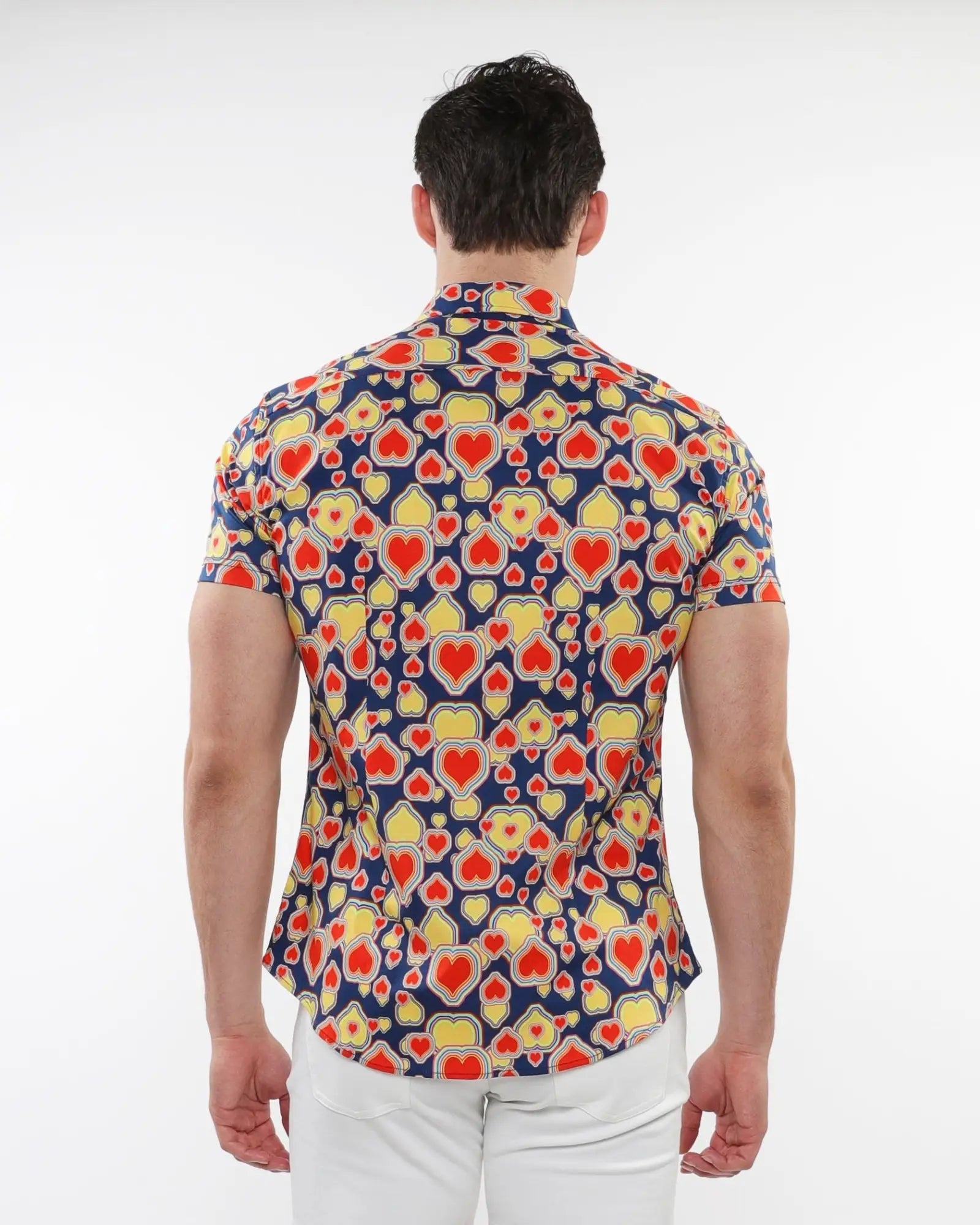 A man wearing a navy blue hearts print stretch knit short sleeve shirt with red and yellow heart patterns
