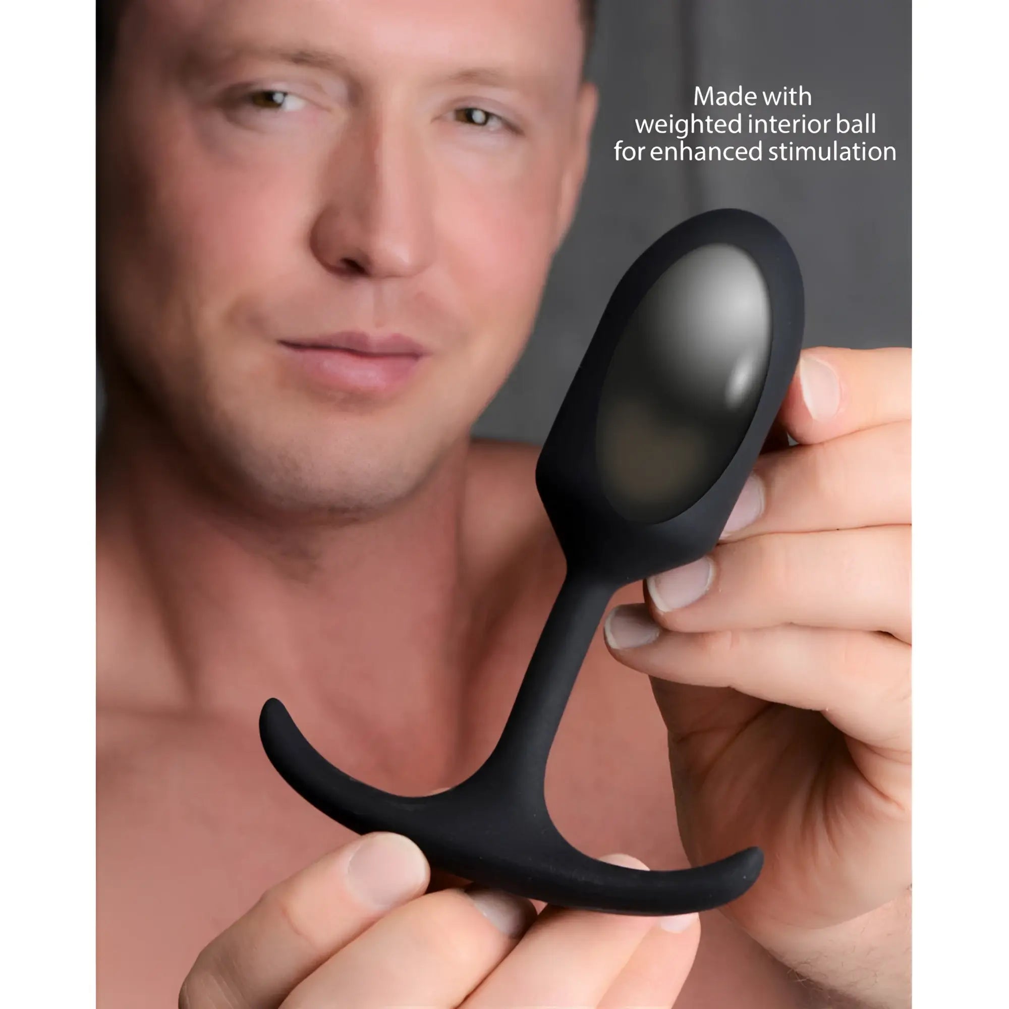 Man holding a black Heavy Hitters Premium Silicone Weighted Bullet Anal Plug with a curved, flared base.