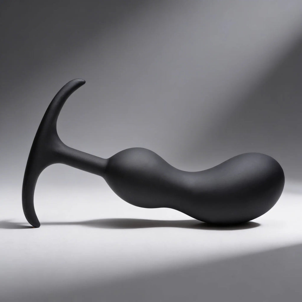 Heavy Hitters matte black silicone prostate plug with a curved, weighted shaft and a flared, ergonomic T-shaped base.