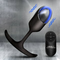 Heavy Hitters black silicone vibrating anal plug with a glowing blue light and matching remote on a metallic background.