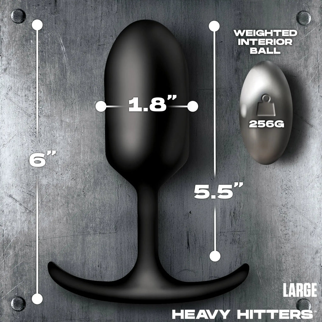 Heavy Hitters black silicone anal plug on a metal background with measurement labels and a 256g interior weighted ball.