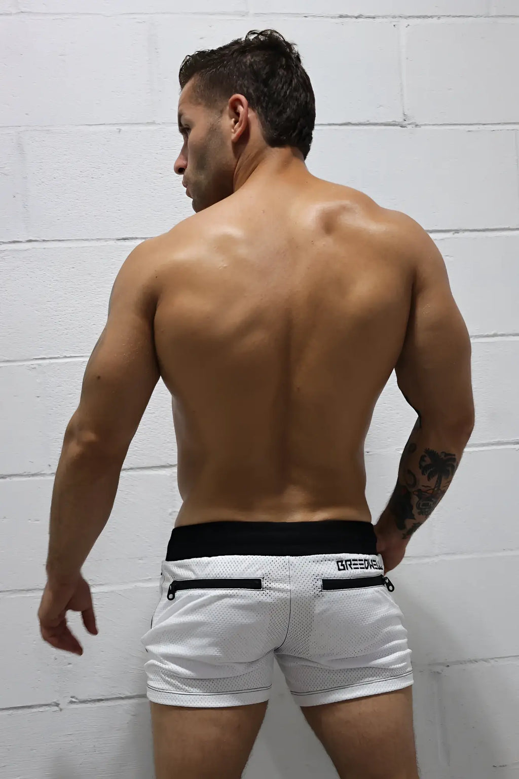 Back view of white mesh creede hook up shorts with black waistband and zipper pockets for athletic use