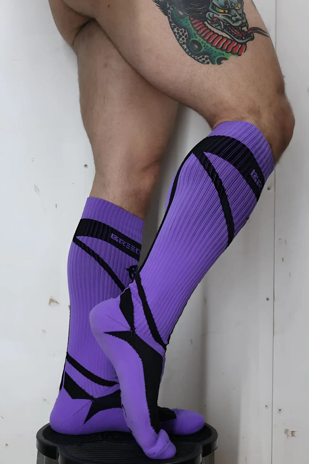 Purple athletic compression hook up socks with black geometric patterns and ribbed texture for performance use